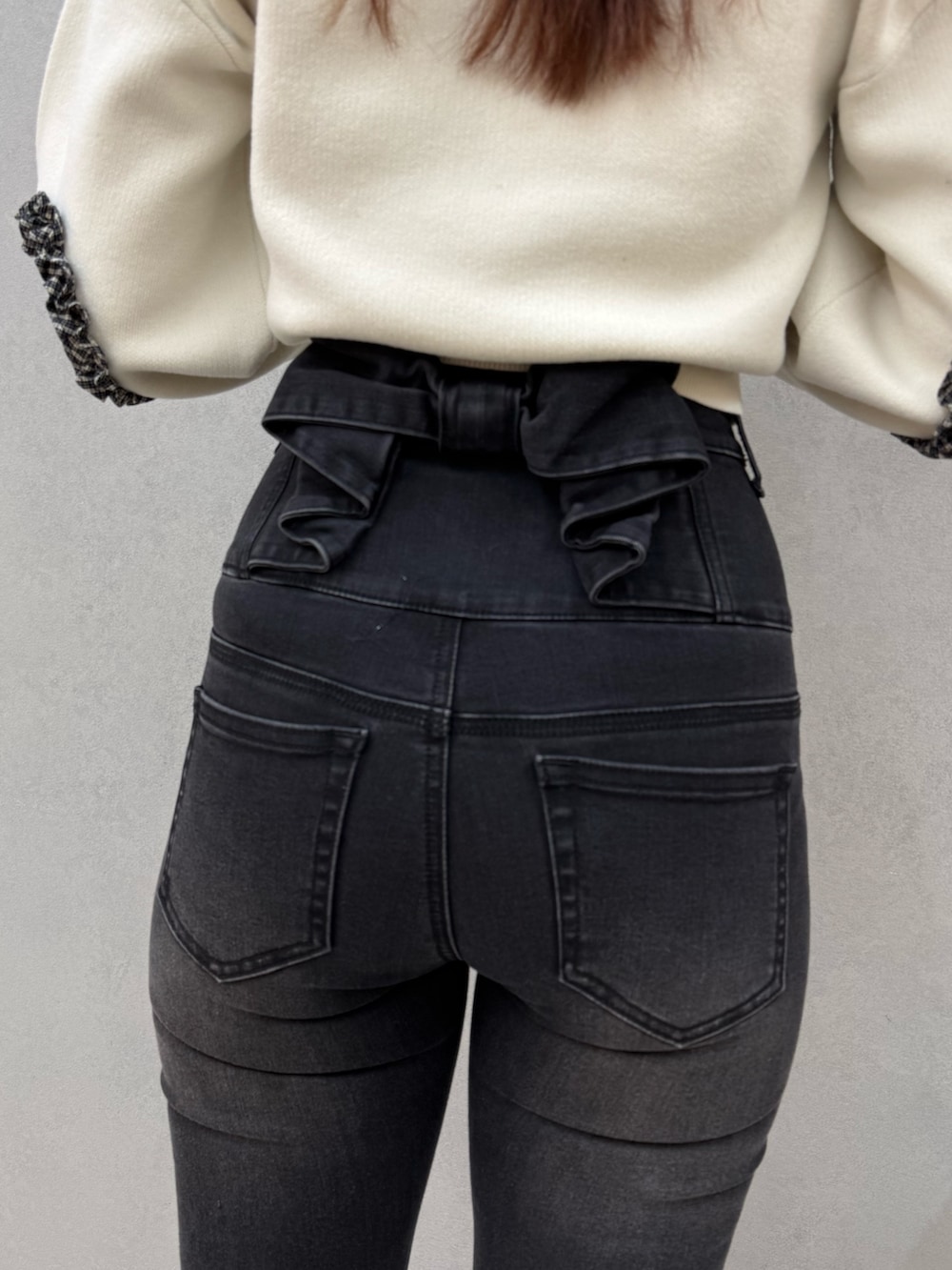 ブラック系のブーツ、ブラック系のデニムパンツ、ホワイト系のニット/セーターを着用したレディースの冬コーディネートの6枚目の写真