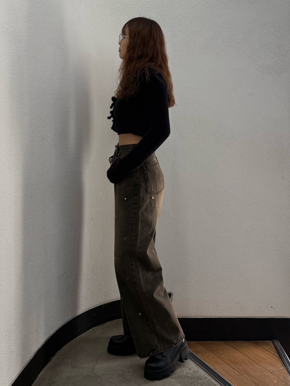 ブラック系のニット/セーター、ブラウン系のデニムパンツ、ブラック系のブーツを着用したレディースの秋コーディネートの2枚目の写真