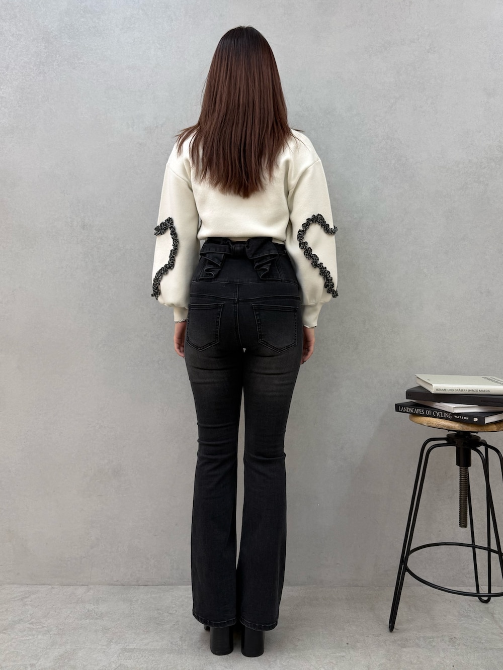 ブラック系のブーツ、ブラック系のデニムパンツ、ホワイト系のニット/セーターを着用したレディースの冬コーディネートの3枚目の写真