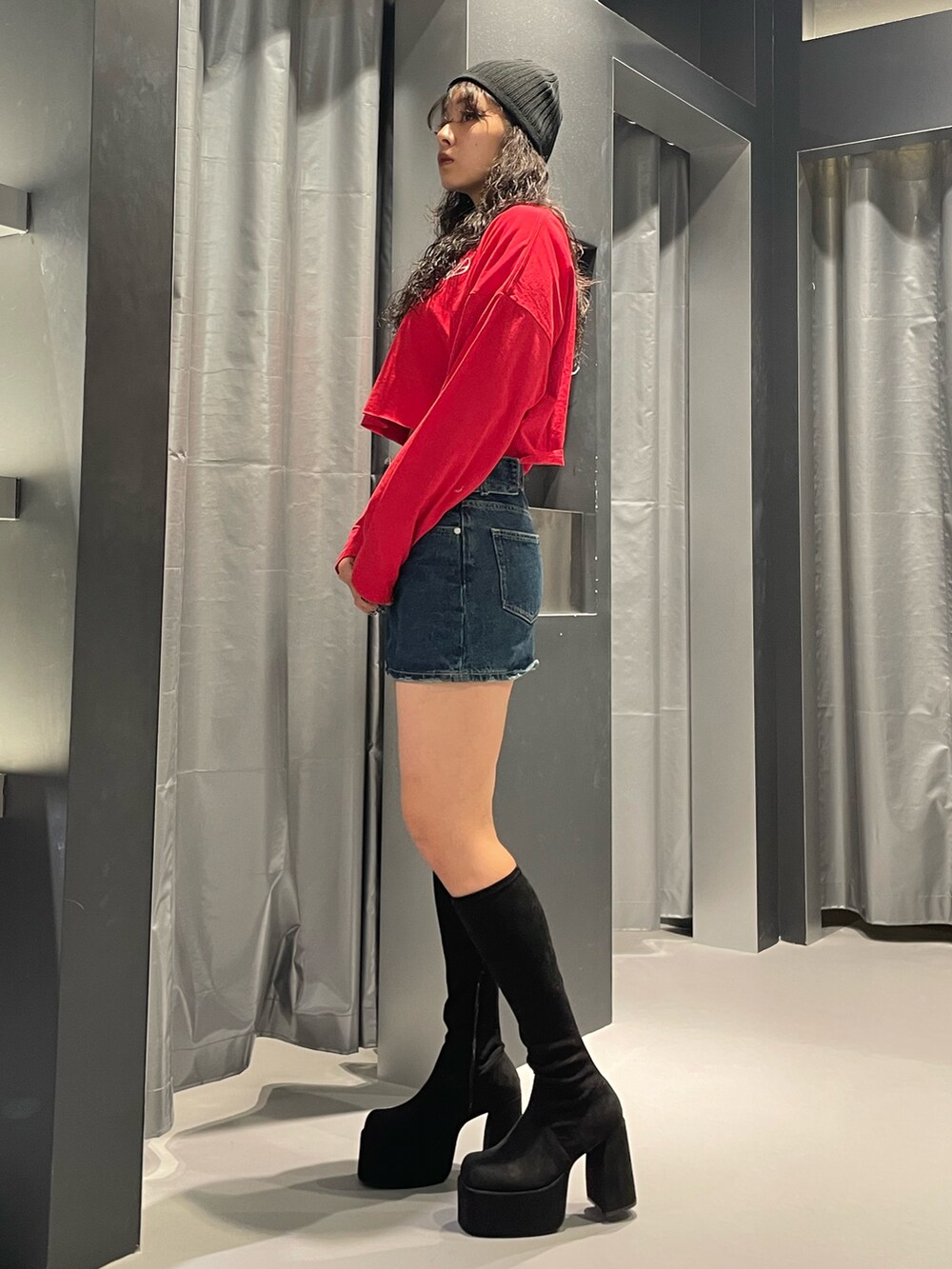 レッド系のTシャツ/カットソー、ブルー系のデニムスカート、その他のブーツを着用したレディースの秋コーディネートの2枚目の写真