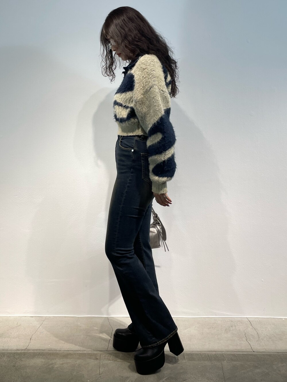 ブルー系のニット/セーター、ブルー系のデニムパンツ、シルバー系のハンドバッグを着用したレディースの秋コーディネートの2枚目の写真