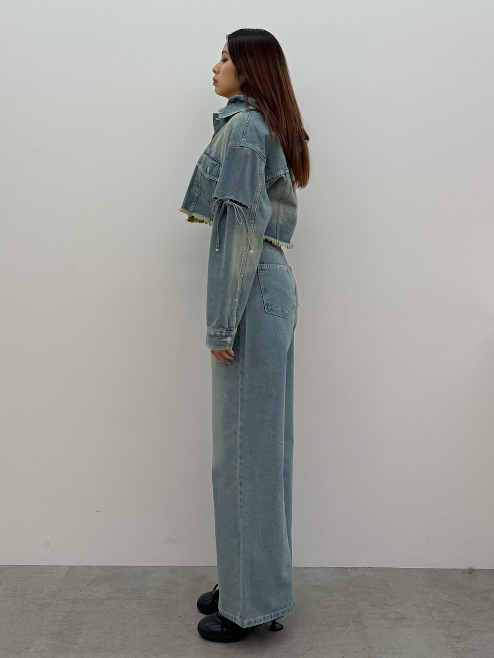 ブルー系のデニムジャケット、ブルー系のデニムパンツ、ブラック系のスニーカーを着用したレディースの冬コーディネートの2枚目の写真