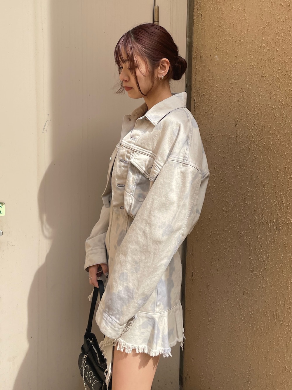 ホワイト系のデニムジャケット、ホワイト系のワンピース、ブラック系のハンドバッグを着用したレディースの春コーディネートの5枚目の写真