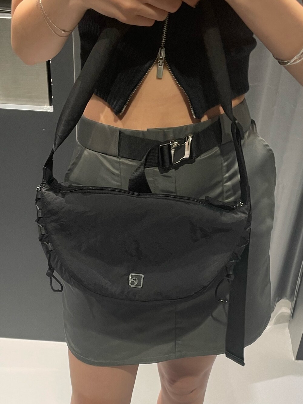 ブラック系のニット/セーター、グレー系のスカート、ブラック系のショルダーバッグを着用したレディースの夏コーディネートの8枚目の写真