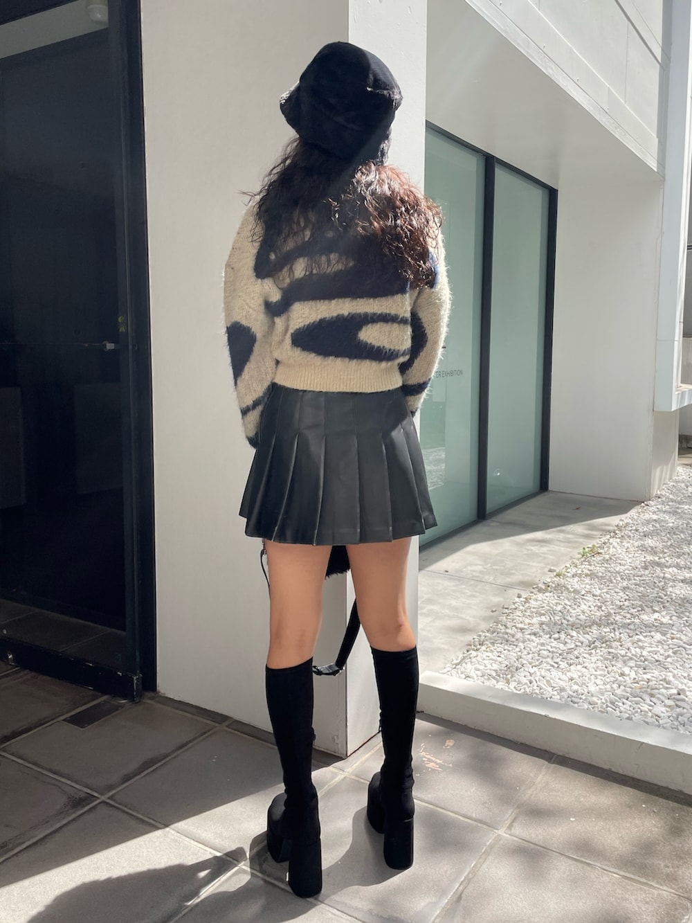 ブルー系のニット/セーター、ブラック系のスカート、ブラック系のハンドバッグを着用したレディースの秋コーディネートの3枚目の写真