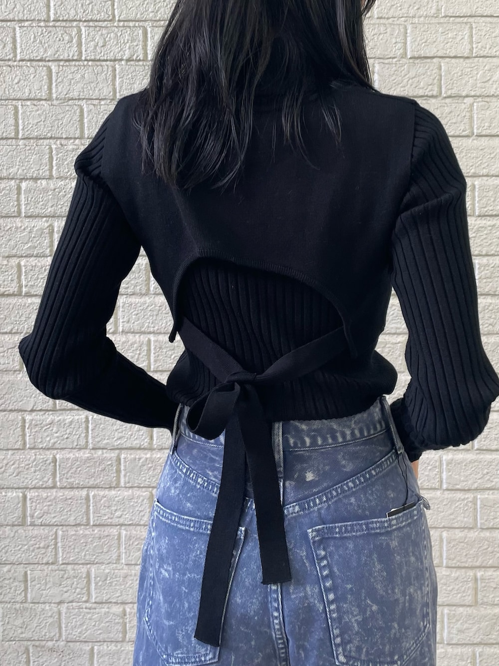 ブラック系のニット/セーター、パープル系のデニムパンツ、ブラック系のブーツを着用したレディースの秋コーディネートの5枚目の写真