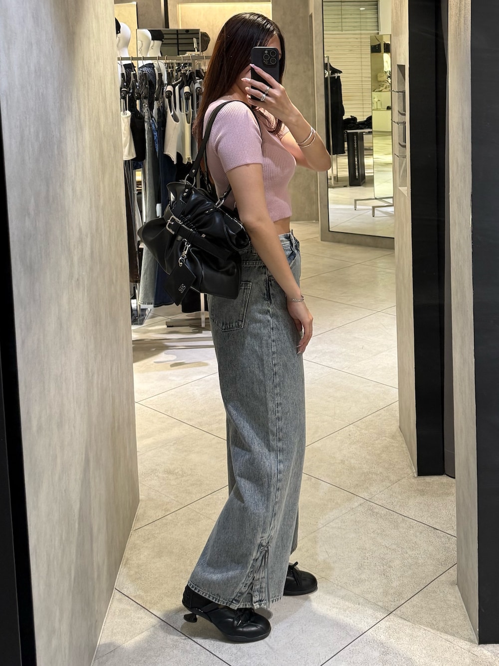 ピンク系のニット/セーター、ブラック系のトートバッグ、ブルー系のデニムパンツを着用したレディースの春コーディネートの2枚目の写真