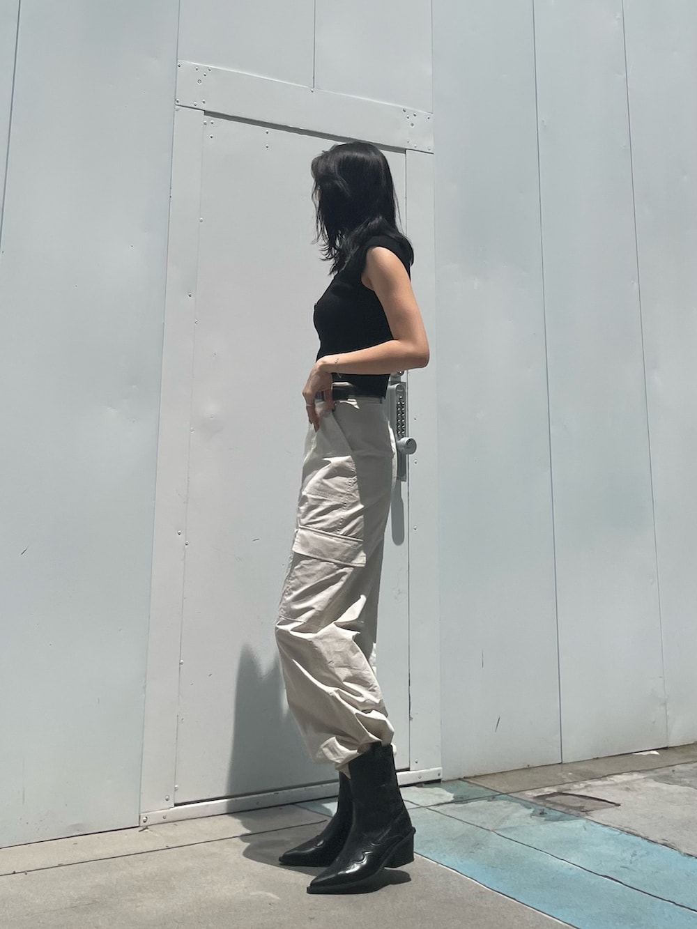 ホワイト系のカーゴパンツ、ブラック系のブーツ、ブラック系のベルトを着用したレディースの夏コーディネートの2枚目の写真