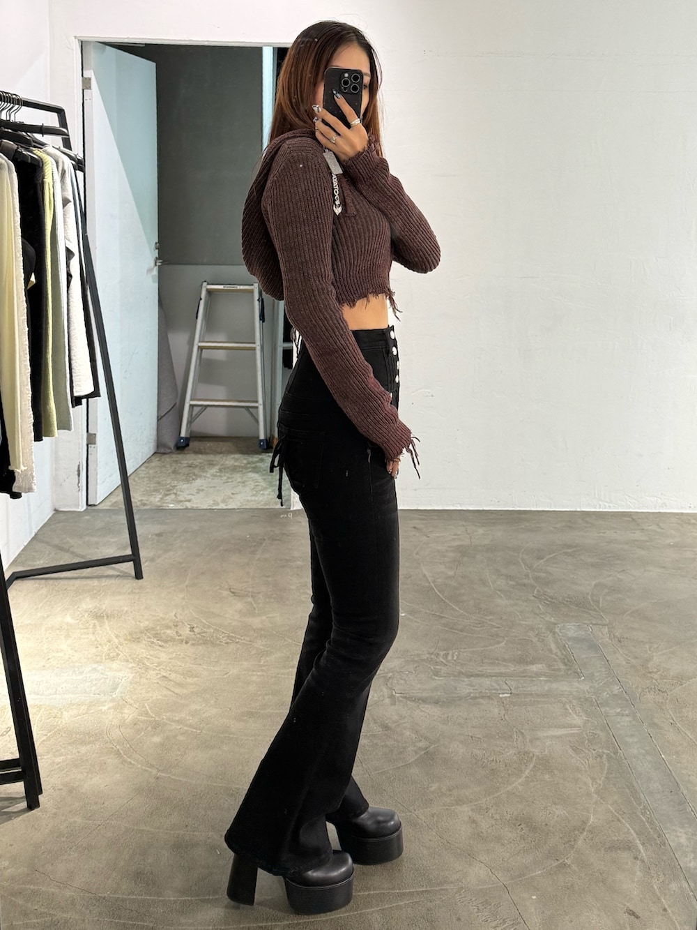 レッド系のニット/セーター、ブラック系のデニムパンツ、ブラック系のブーツを着用したレディースの冬コーディネートの2枚目の写真