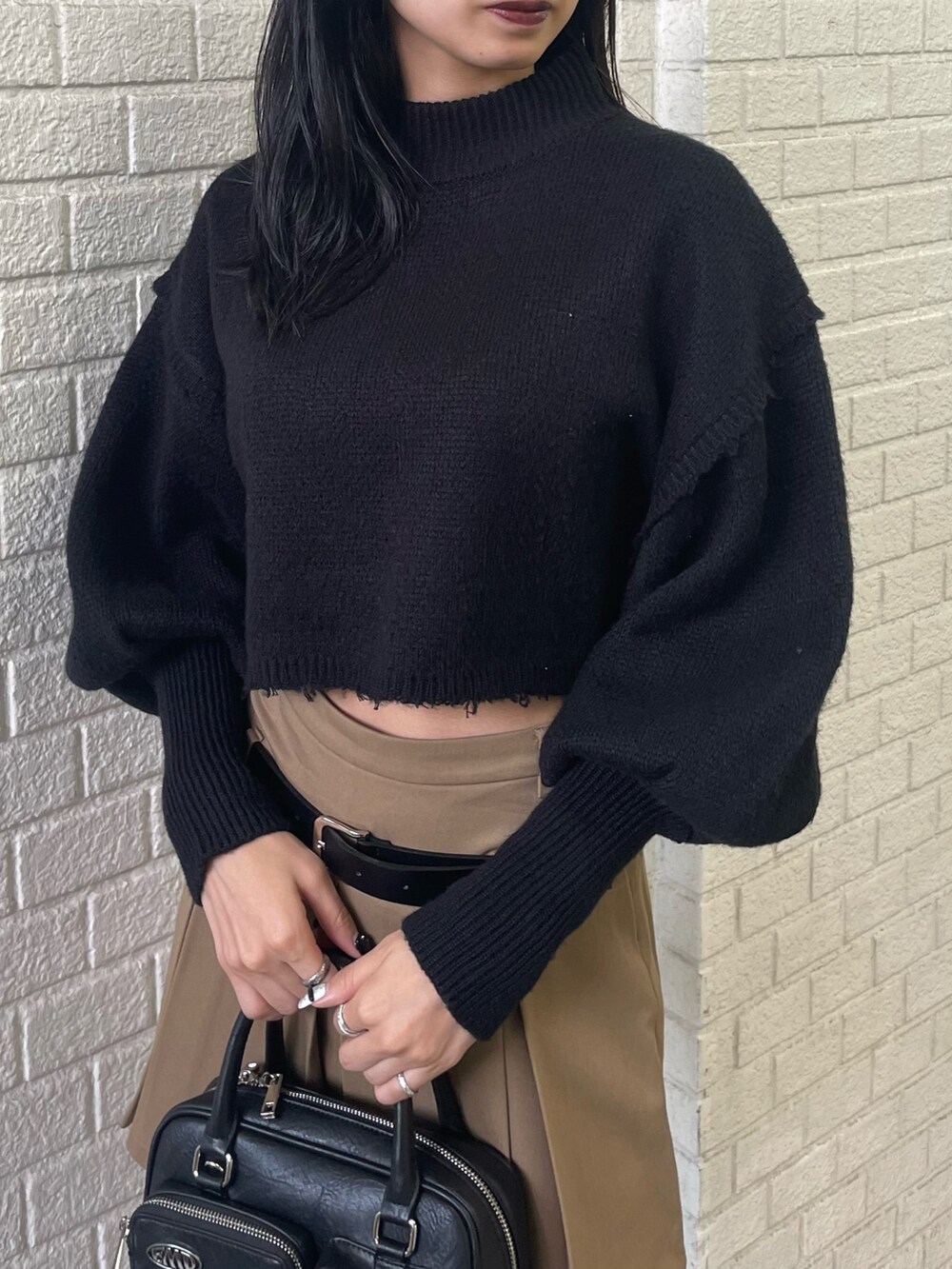 ブラック系のニット/セーター、ブラック系のブルゾン、ベージュ系のスカートを着用したレディースの秋コーディネートの7枚目の写真