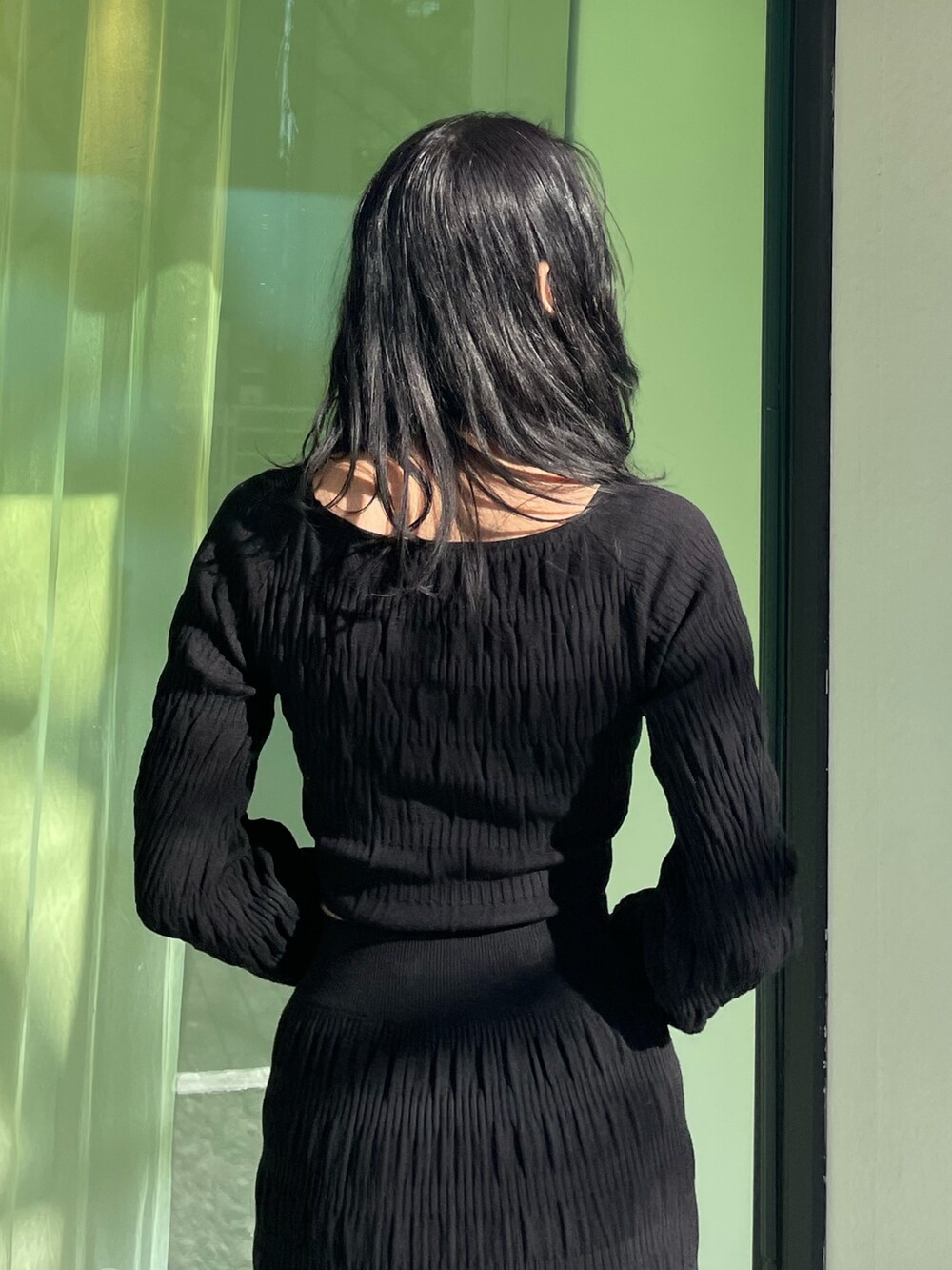 ブラック系のニット/セーター、ブラック系のスカート、ブラック系のブーツを着用したレディースの春コーディネートの6枚目の写真