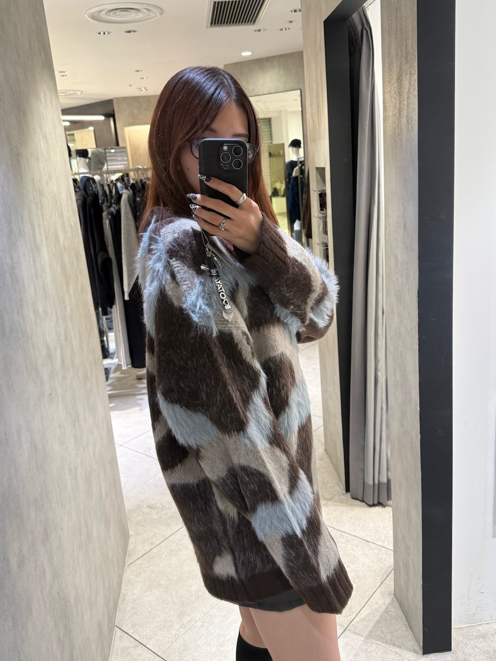 ブラウン系のニット/セーター、ブラック系のスカート、ブラック系のブーツを着用したレディースの秋コーディネートの5枚目の写真