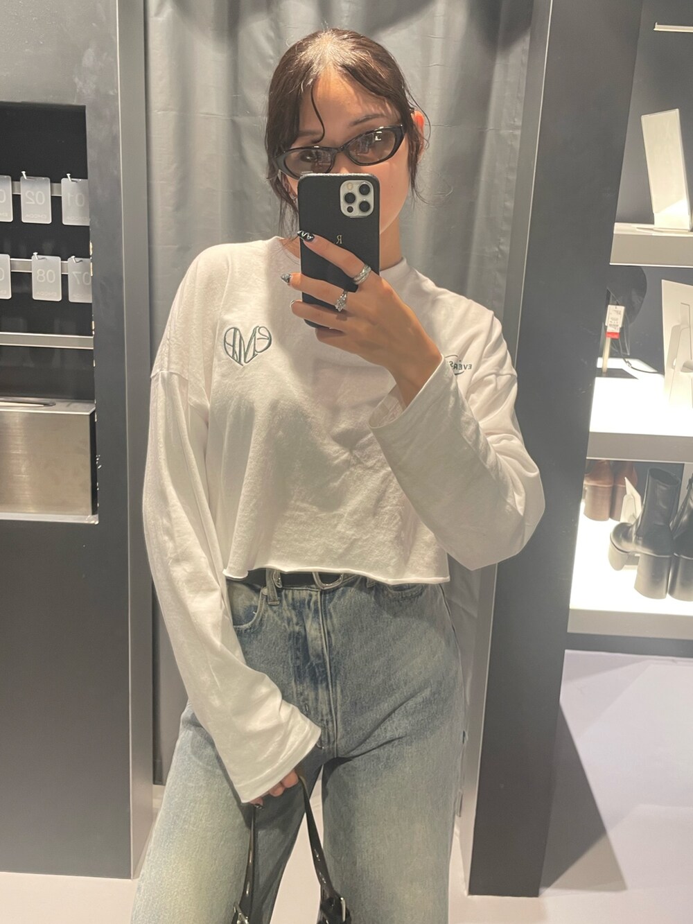 ホワイト系のTシャツ/カットソー、ブルー系のデニムパンツ、ブラック系のハンドバッグを着用したレディースの秋コーディネートの4枚目の写真