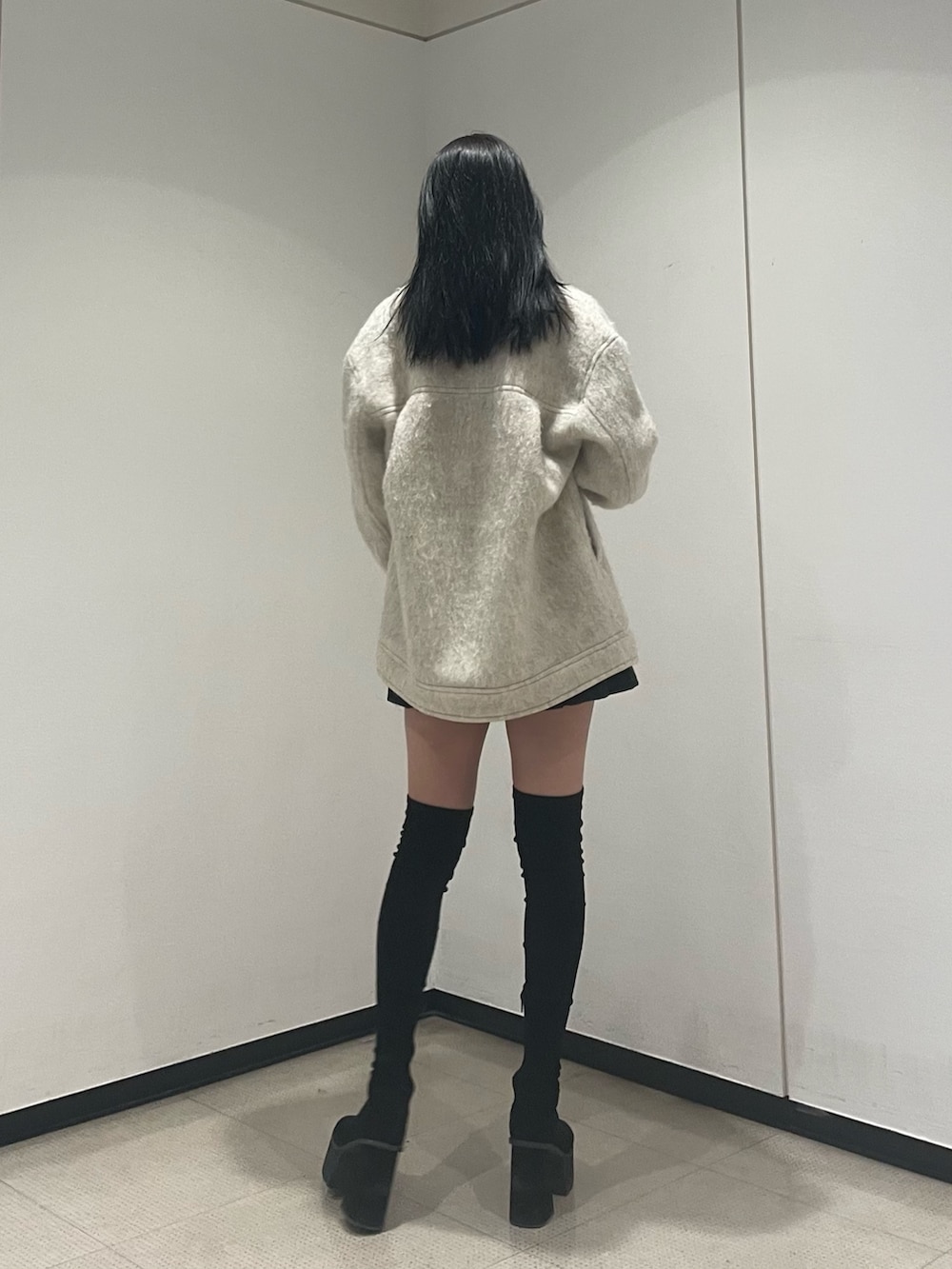 ホワイト系のニット/セーター、ホワイト系のピーコート、ブラック系のスカートを着用したレディースの冬コーディネートの3枚目の写真