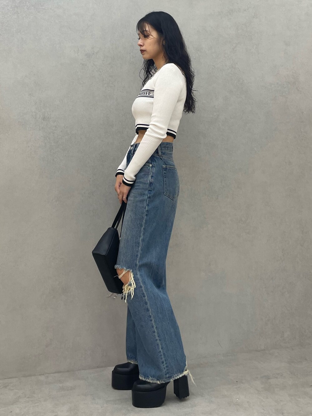 ホワイト系のニット/セーター、ブルー系のデニムパンツ、ブラック系のショルダーバッグを着用したレディースの夏コーディネートの2枚目の写真