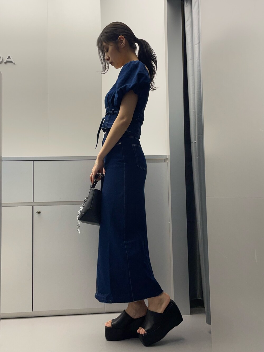 ブルー系のシャツ/ブラウス、ブルー系のスカート、ブラック系のハンドバッグを着用したレディースの春コーディネートの2枚目の写真