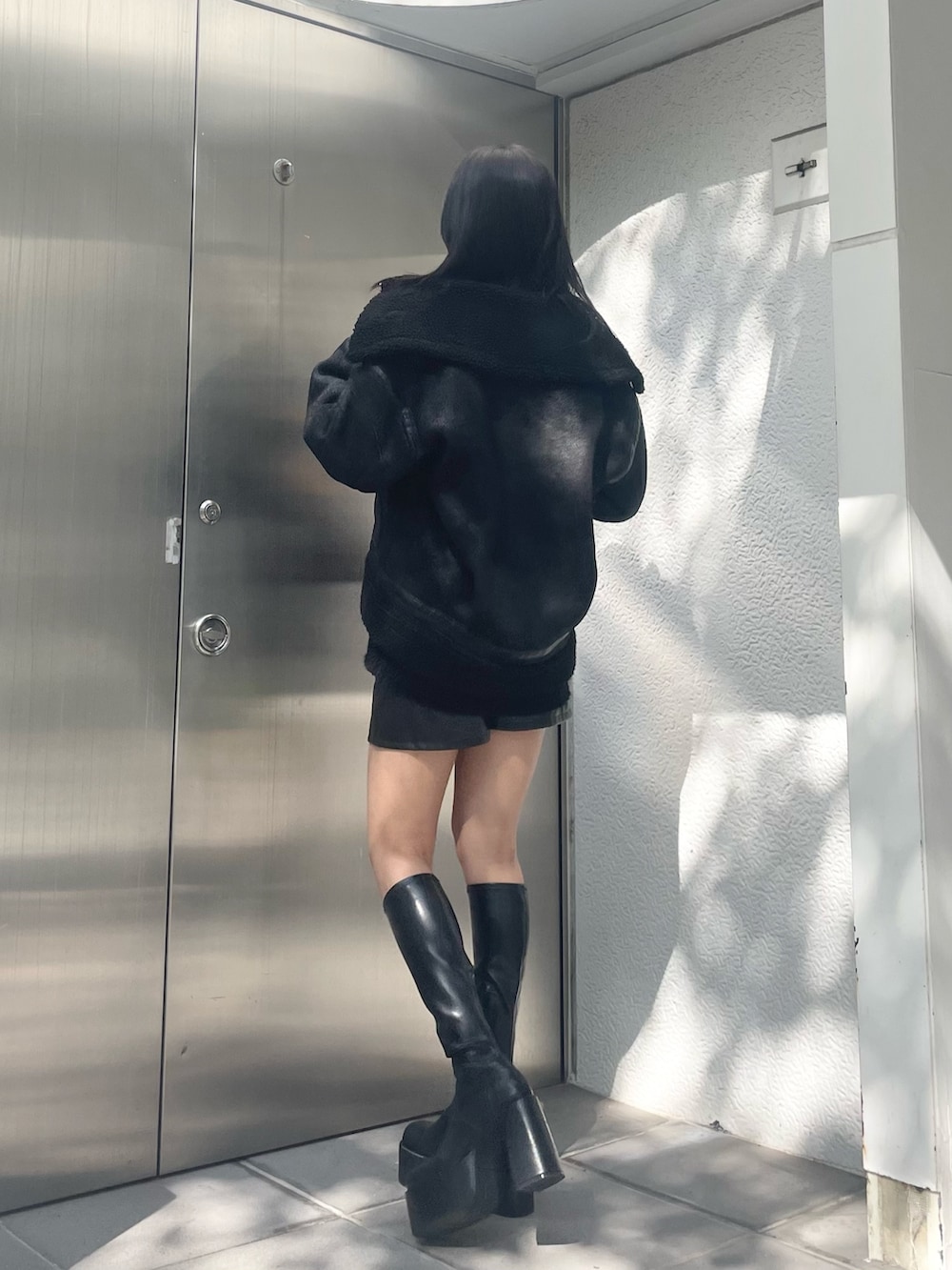 オレンジ系のニット/セーター、ブラック系のムートンコート、ブラック系のその他パンツを着用したレディースの秋コーディネートの3枚目の写真