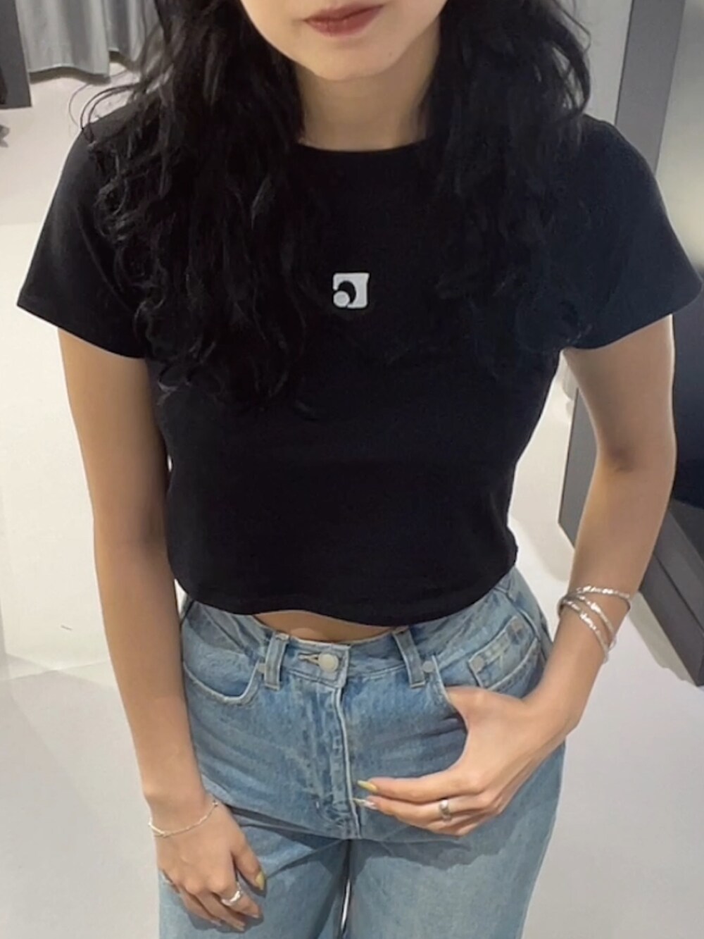 ブラック系のTシャツ/カットソー、ブルー系のデニムパンツ、シルバー系のサンダルを着用したレディースの春コーディネートの3枚目の写真