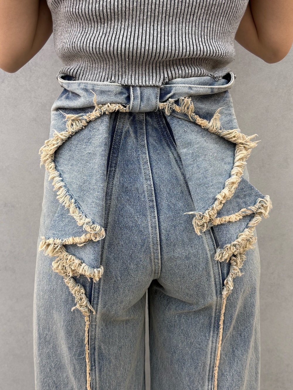 ブラック系のニット/セーター、ブルー系のデニムパンツ、ブラック系のサンダルを着用したレディースの春コーディネートの5枚目の写真