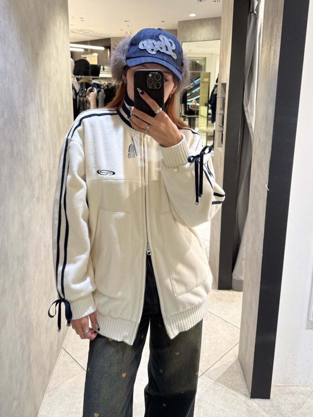 ブラック系のブーツ、ブルー系のデニムパンツ、ホワイト系のブルゾンを着用したレディースの秋コーディネートの4枚目の写真