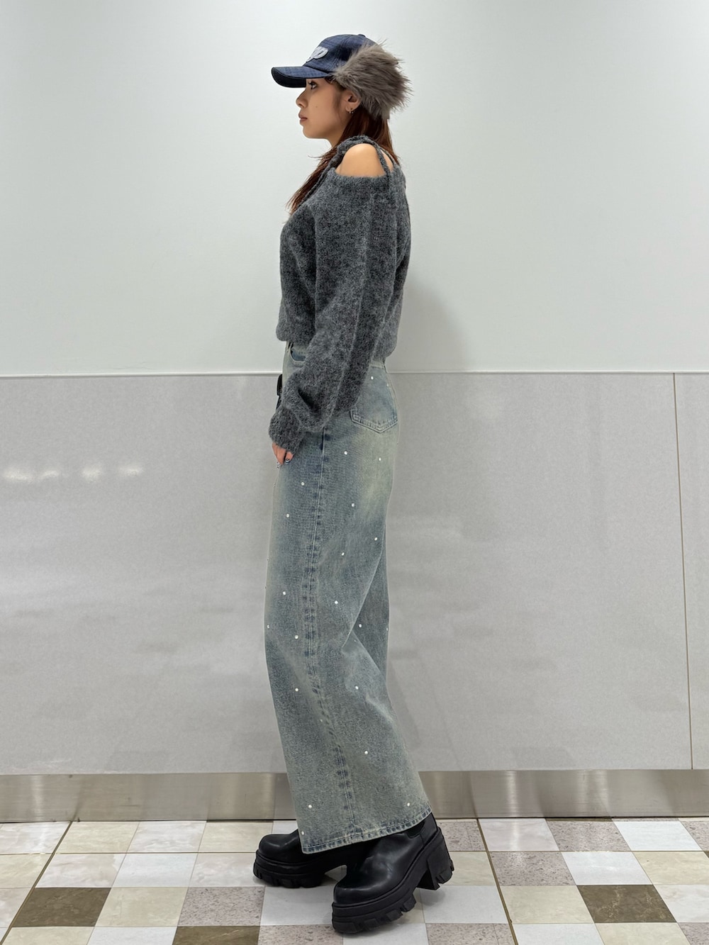 グレー系のニット/セーター、ブラック系のブーツ、ブルー系のデニムパンツを着用したレディースの冬コーディネートの2枚目の写真