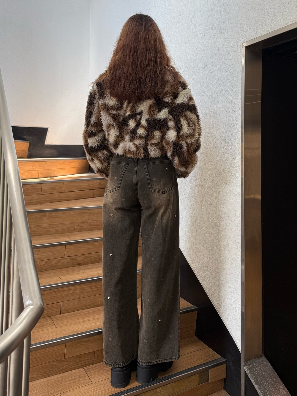 ブラウン系のブルゾン、ブラック系のニット/セーター、ブラウン系のデニムパンツを着用したレディースの秋コーディネートの3枚目の写真