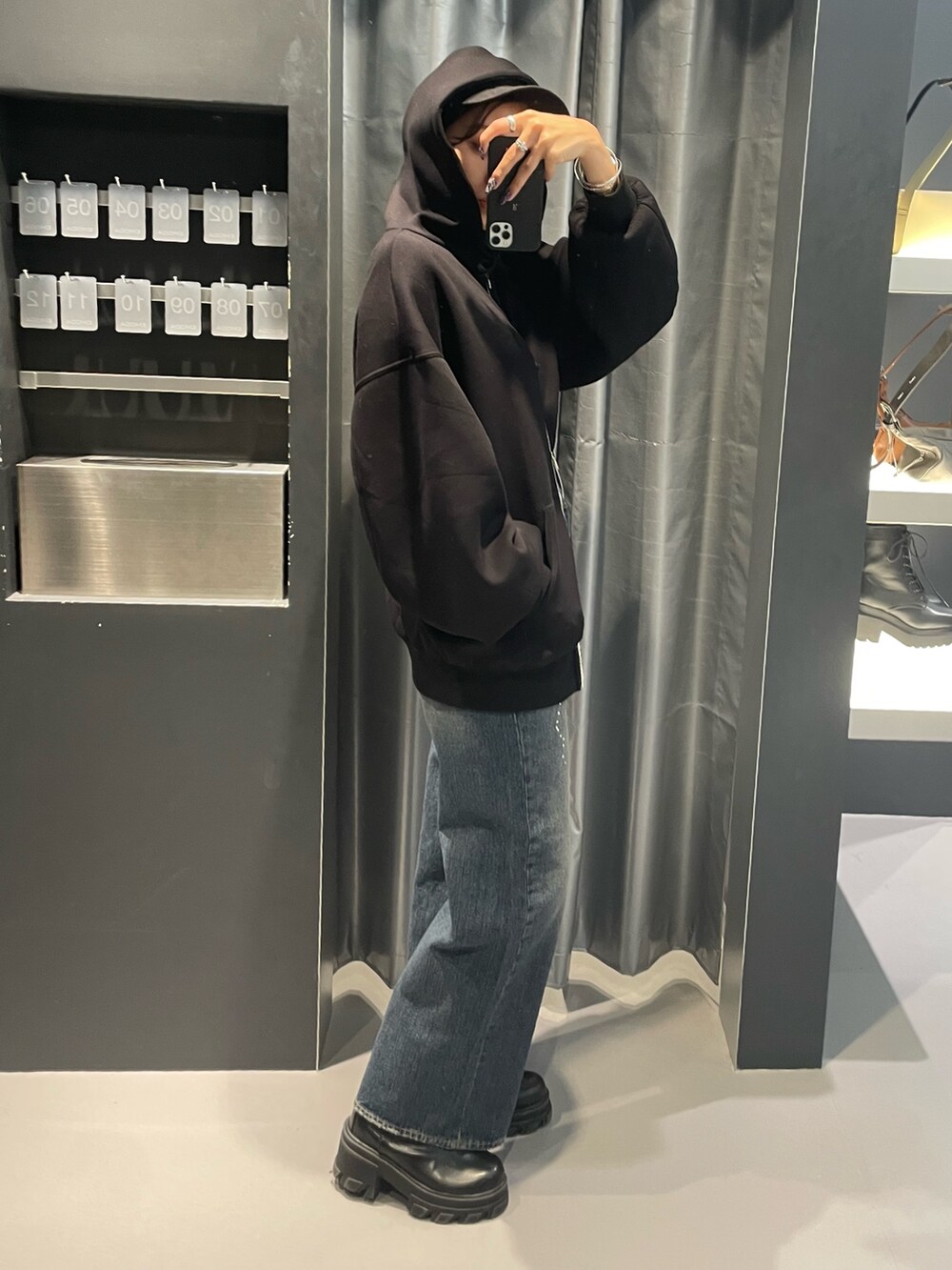ブラック系のパーカー、ブルー系のデニムパンツ、ブラック系のブーツを着用したレディースの秋コーディネートの2枚目の写真