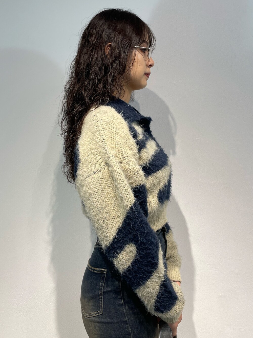 ブルー系のニット/セーター、ブルー系のデニムパンツ、シルバー系のハンドバッグを着用したレディースの秋コーディネートの5枚目の写真