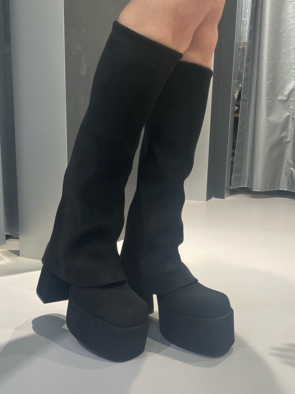 グレー系のニット/セーター、グレー系のスカート、ブラック系のブーツを着用したレディースの秋コーディネートの8枚目の写真