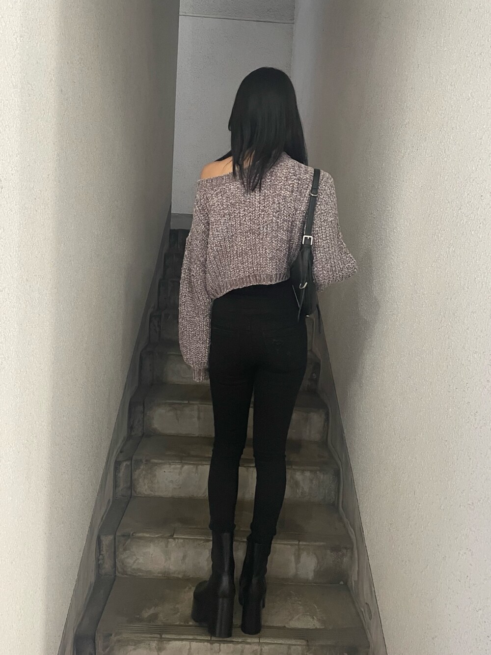 グレー系のニット/セーター、ブラック系のハンドバッグ、ブラック系のデニムパンツを着用したレディースの冬コーディネートの3枚目の写真