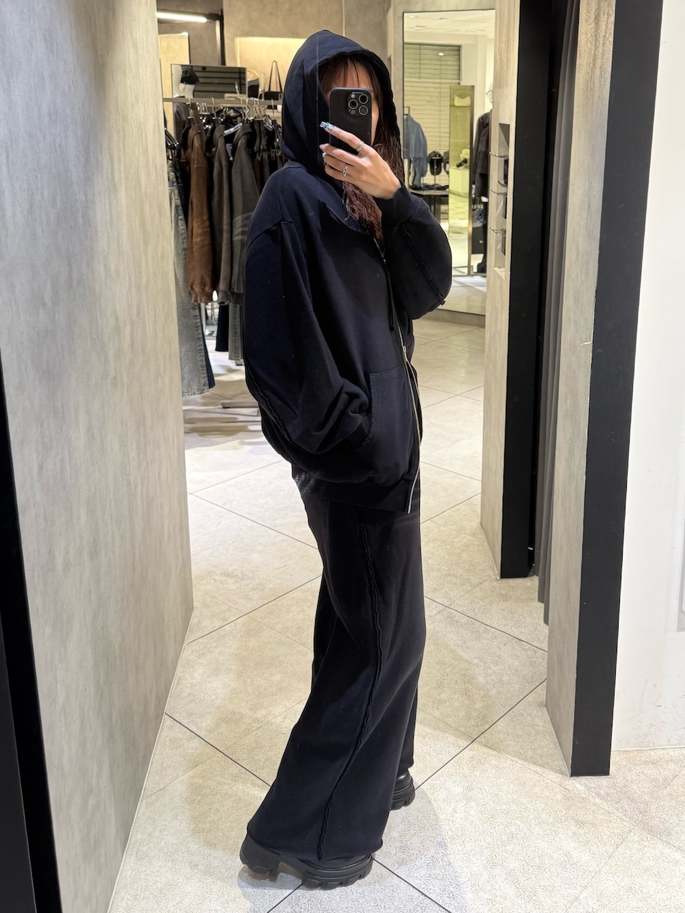 ブラック系のパーカー、ブラック系のスウェットパンツ、ブラック系のブーツを着用したレディースの秋コーディネートの2枚目の写真