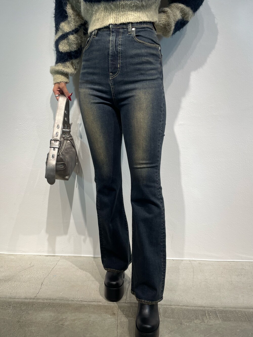 ブルー系のニット/セーター、ブルー系のデニムパンツ、シルバー系のハンドバッグを着用したレディースの秋コーディネートの7枚目の写真