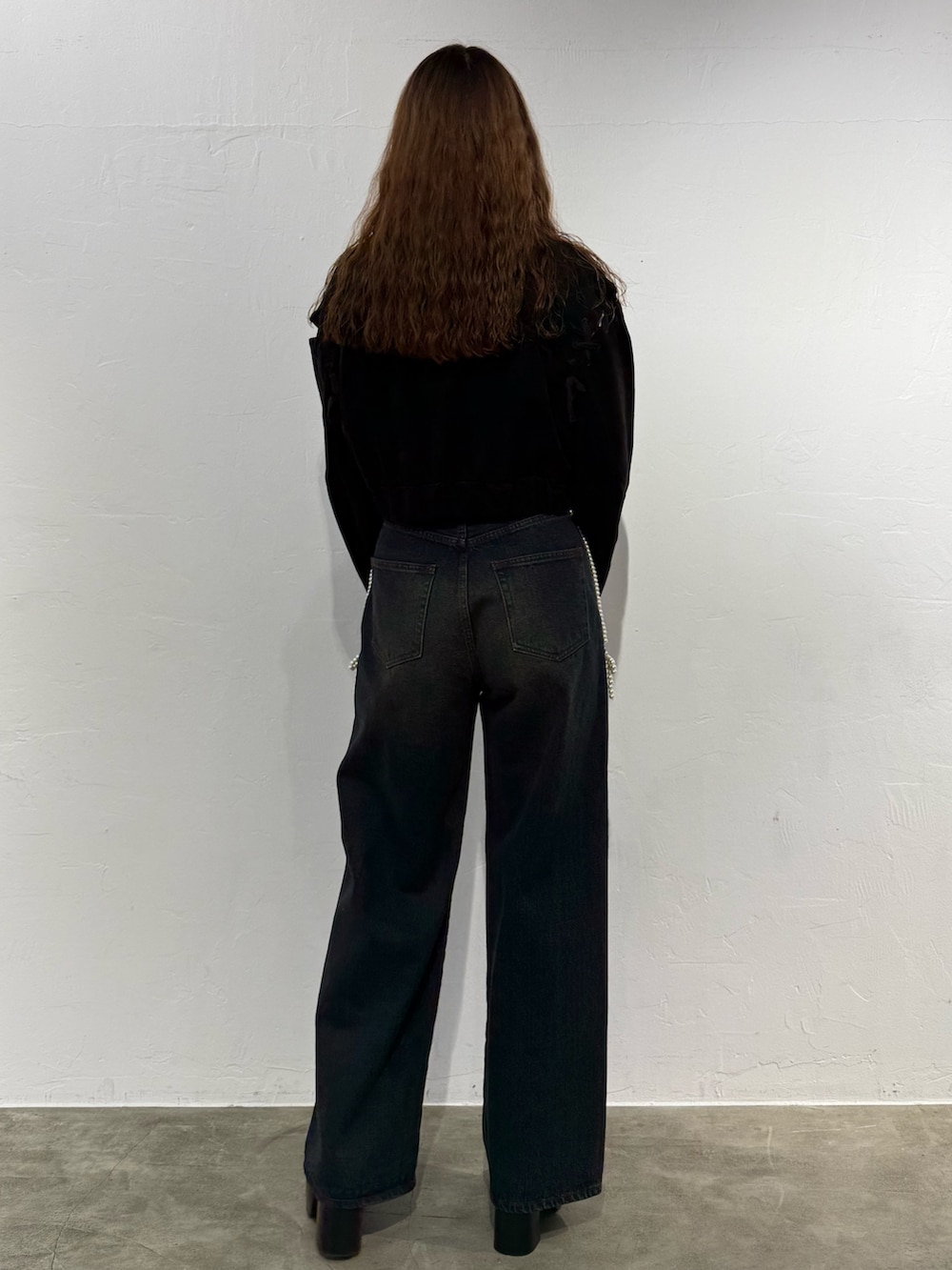 ホワイト系のニット/セーター、ブラック系のブルゾン、ブルー系のデニムパンツを着用したレディースの秋コーディネートの3枚目の写真