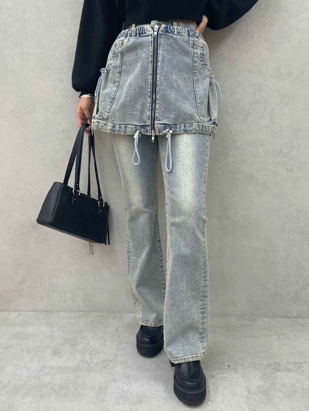 ブラック系のニット/セーター、ブルー系のデニムパンツ、ブラック系のショルダーバッグを着用したレディースの夏コーディネートの7枚目の写真