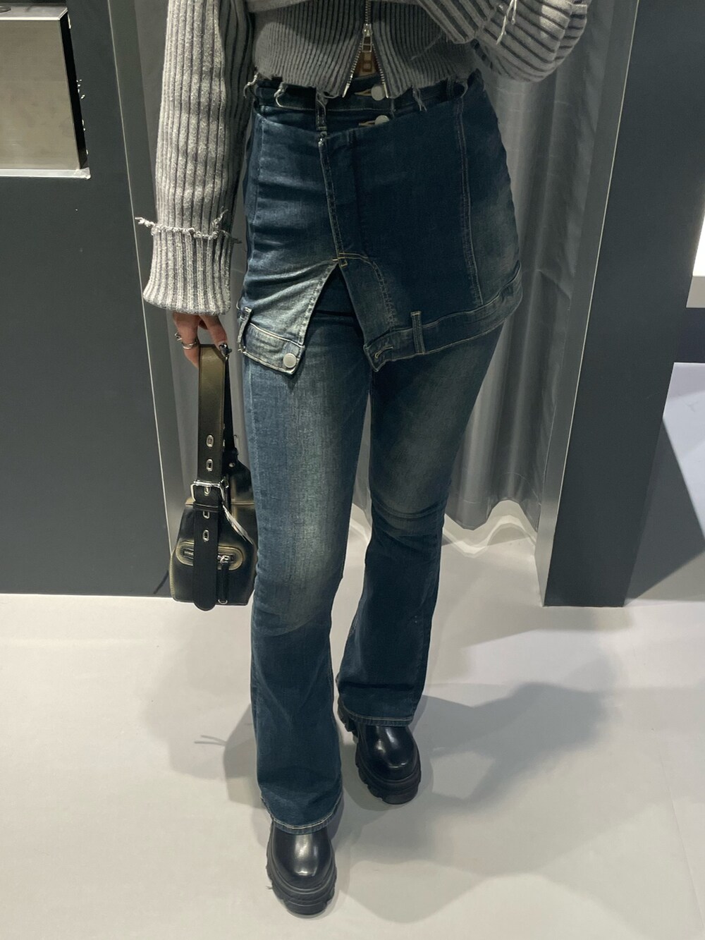 グレー系のニット/セーター、ブルー系のデニムパンツ、ブラック系のハンドバッグを着用したレディースの秋コーディネートの6枚目の写真