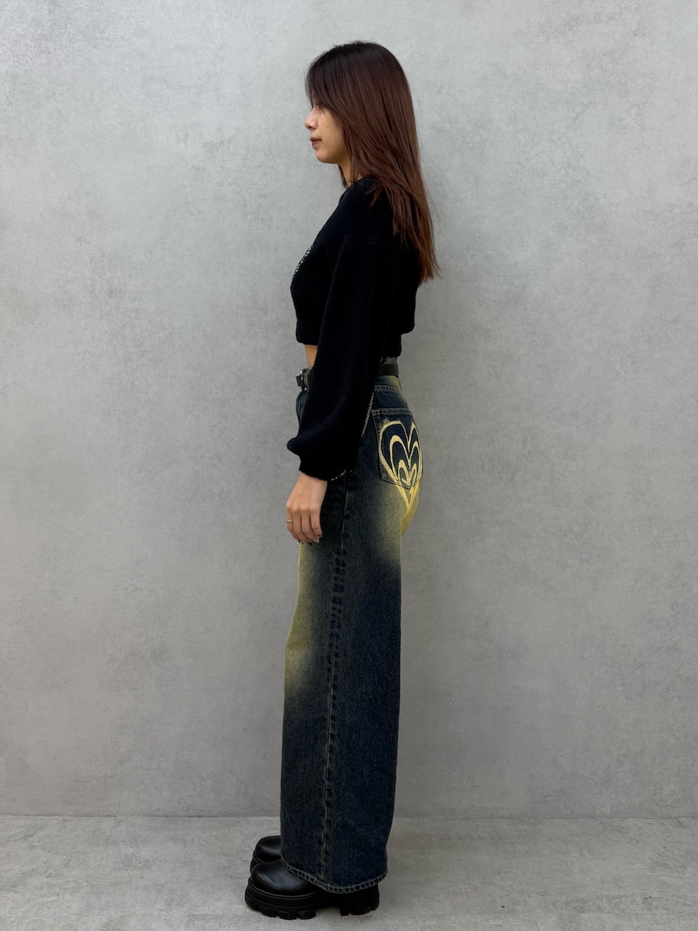 ブラック系のニット/セーター、ブルー系のデニムパンツ、ブラック系のブーツを着用したレディースの冬コーディネートの2枚目の写真