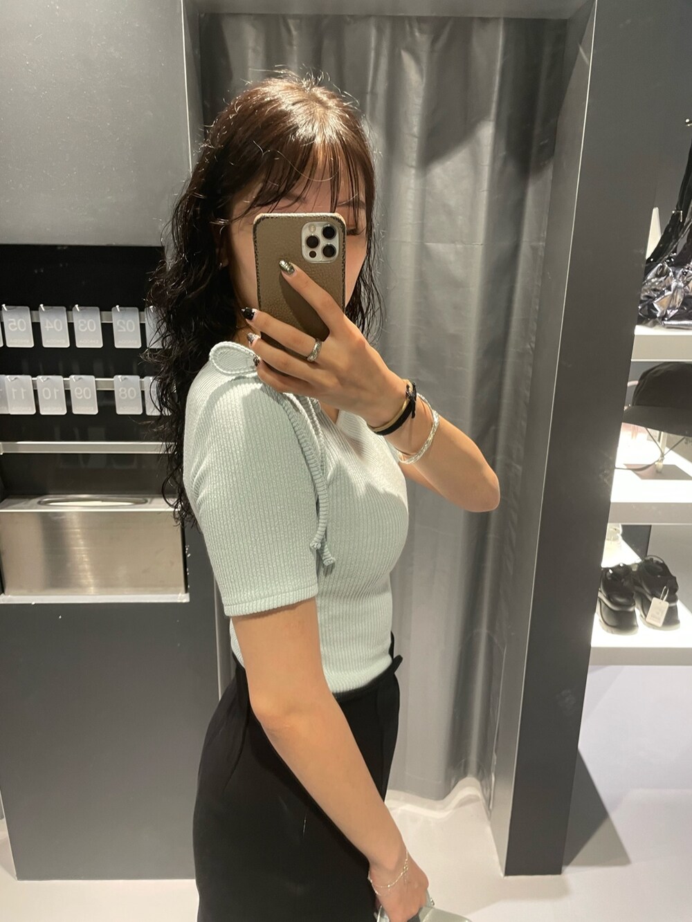 ブルー系のTシャツ/カットソー、ブラック系のスカート、シルバー系のハンドバッグを着用したレディースの夏コーディネートの5枚目の写真