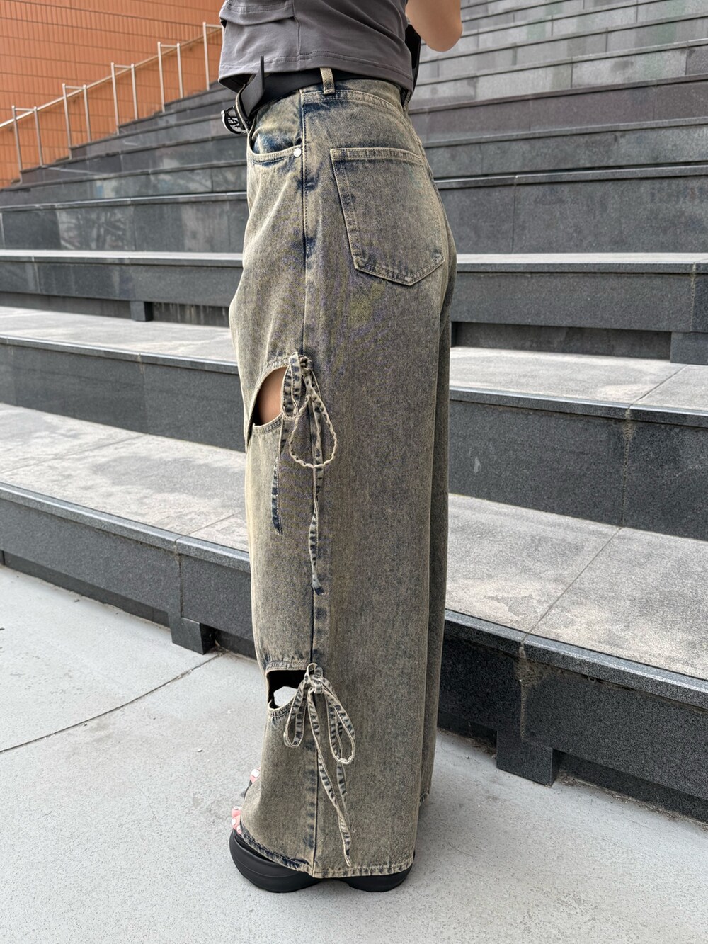 ブラック系のニット/セーター、ブルー系のデニムパンツ、ブラック系のサンダルを着用したレディースの夏コーディネートの8枚目の写真