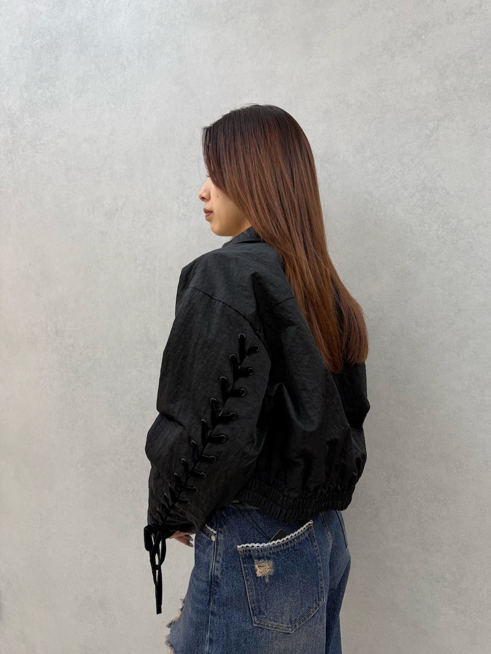 ブラック系のブルゾン、ホワイト系のニット/セーター、ブルー系のデニムパンツを着用したレディースの冬コーディネートの5枚目の写真