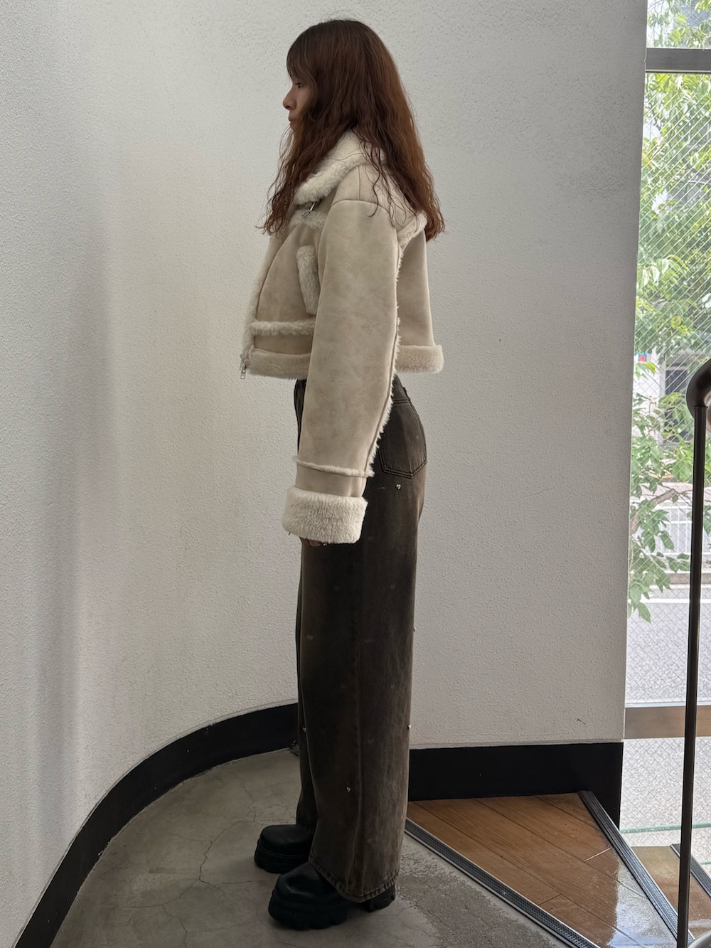 ホワイト系のブルゾン、ブラック系のTシャツ/カットソー、ブラウン系のデニムパンツを着用したレディースの秋コーディネートの2枚目の写真