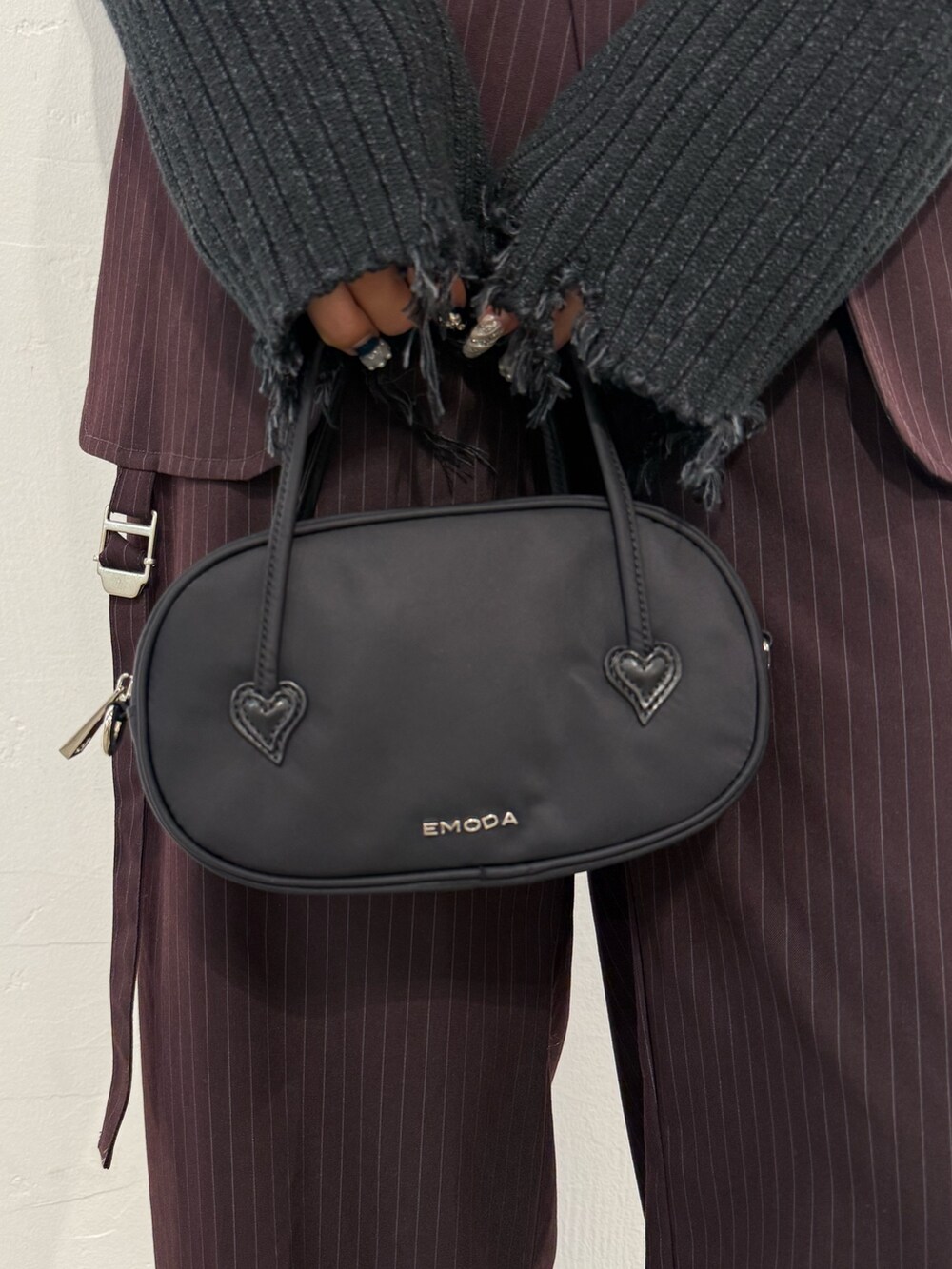 ブラック系のニット/セーター、ブラウン系のその他パンツ、ブラック系のハンドバッグを着用したレディースの秋コーディネートの6枚目の写真