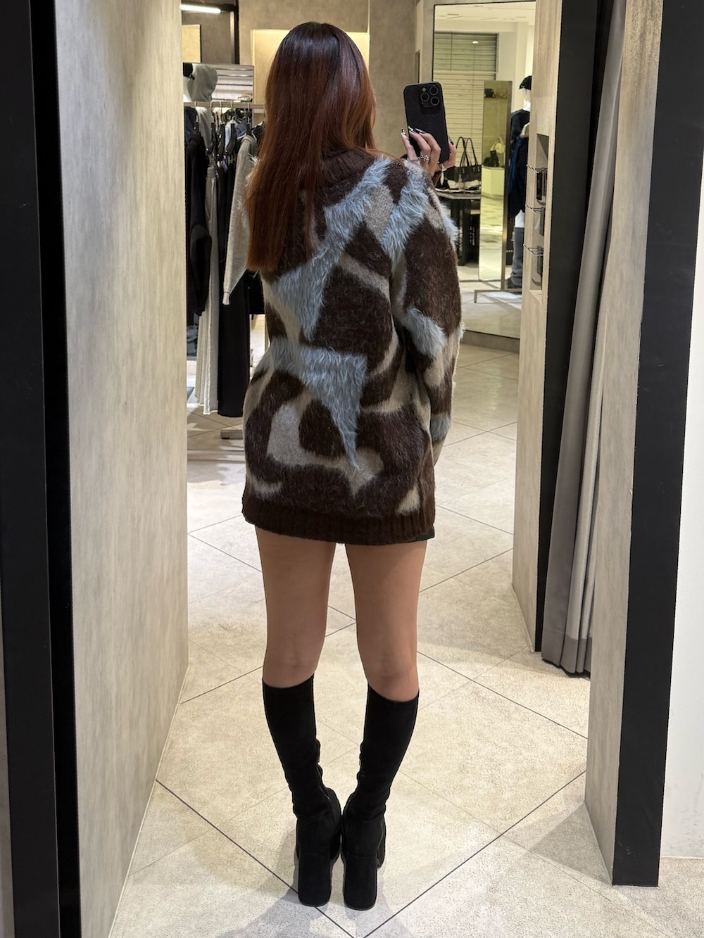 ブラウン系のニット/セーター、ブラック系のスカート、ブラック系のブーツを着用したレディースの秋コーディネートの3枚目の写真