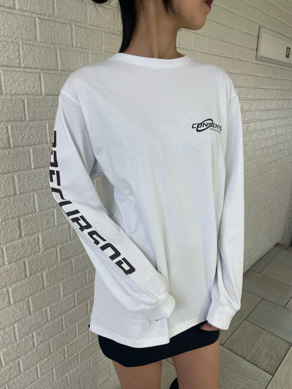 ホワイト系のTシャツ/カットソー、ホワイト系のダウンベスト、ブラック系のスカートを着用したレディースの秋コーディネートの7枚目の写真