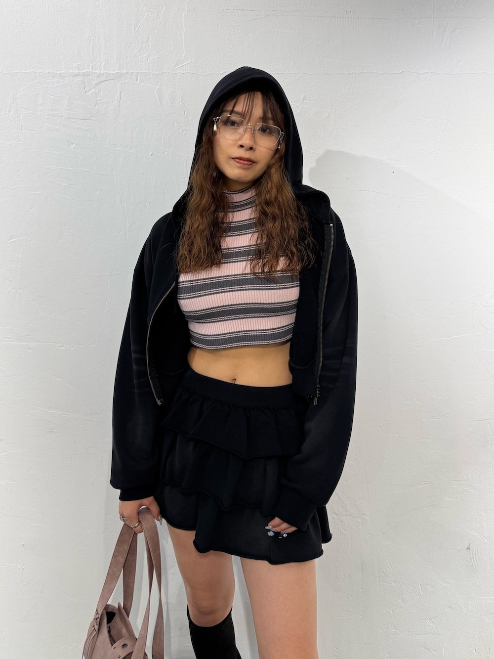 ピンク系のニット/セーター、ブラック系のパーカー、ブラック系のスカートを着用したレディースの秋コーディネートの4枚目の写真