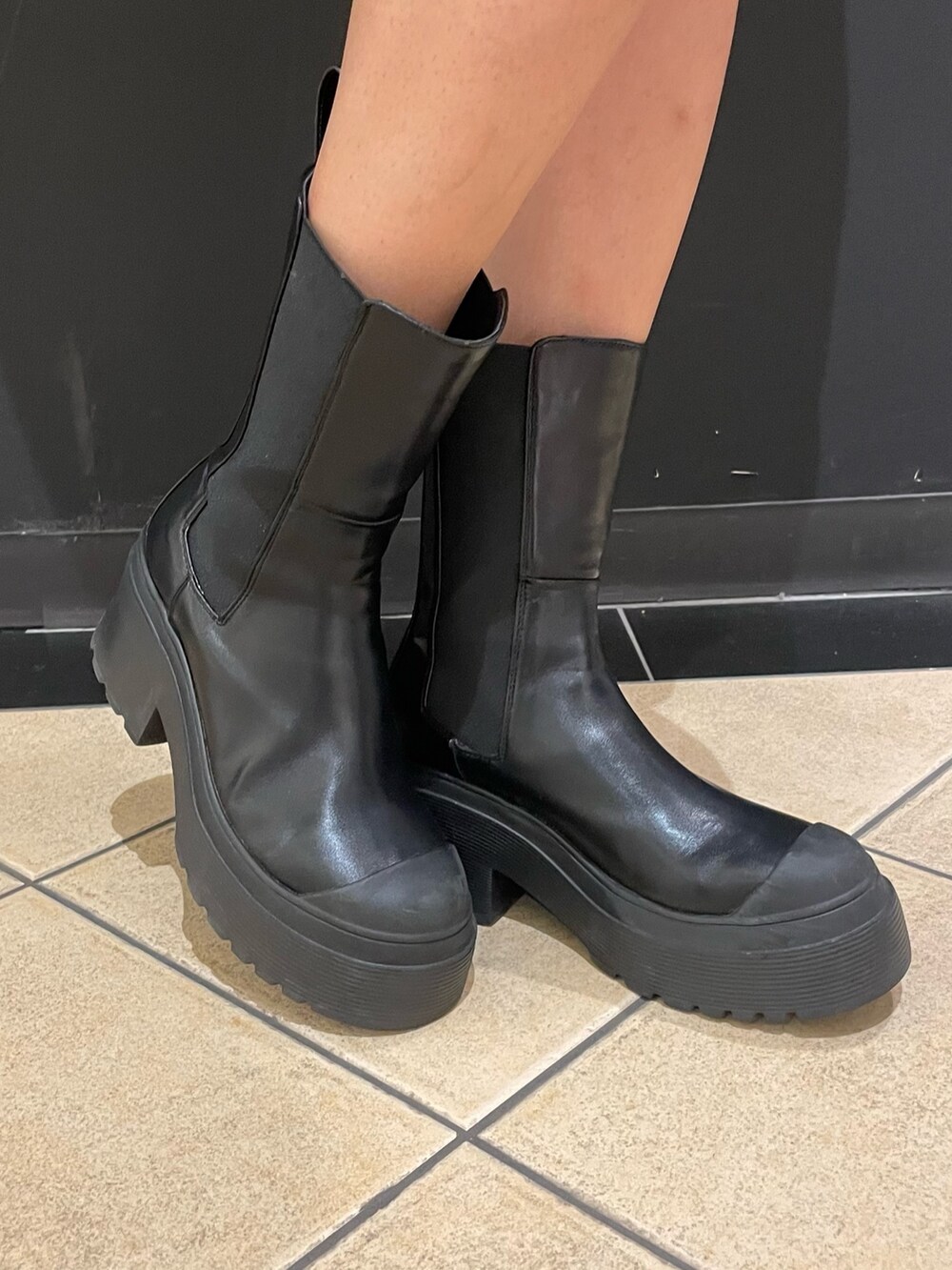 グレー系のワンピース、ブラック系のハンドバッグ、ブラック系のスカートを着用したレディースの秋コーディネートの6枚目の写真