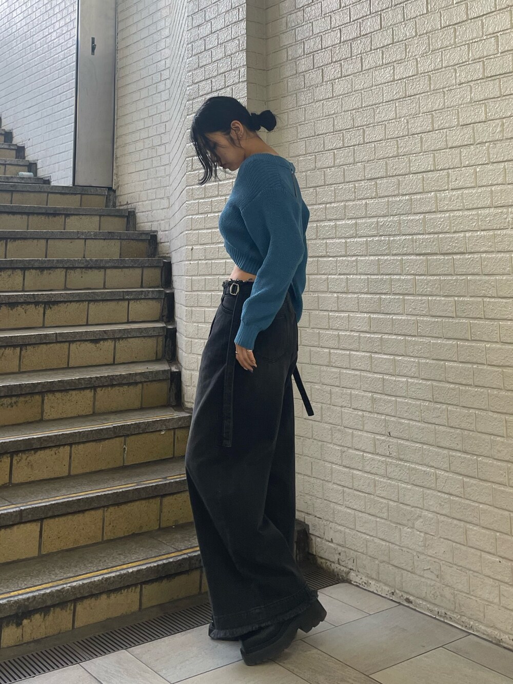 ブルー系のニット/セーター、ブラック系のデニムパンツ、ブラック系のブーツを着用したレディースの春コーディネートの2枚目の写真