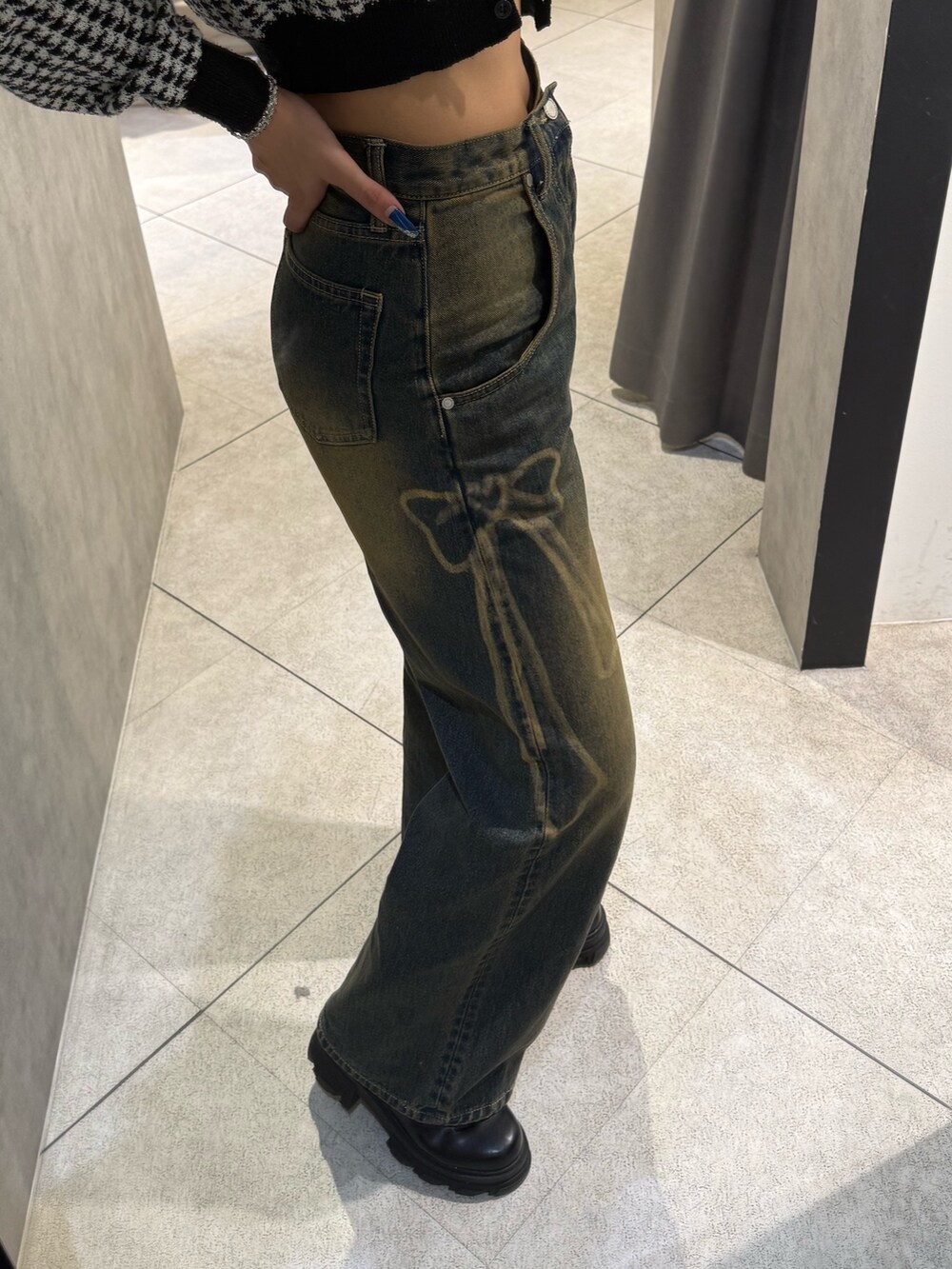 ブラック系のニット/セーター、ブルー系のデニムパンツ、ブラック系のブーツを着用したレディースの秋コーディネートの6枚目の写真