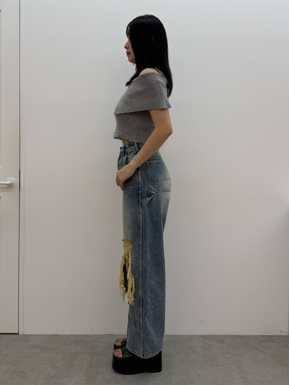 グレー系のニット/セーター、ブルー系のデニムパンツ、ブラック系のサンダルを着用したレディースの春コーディネートの2枚目の写真