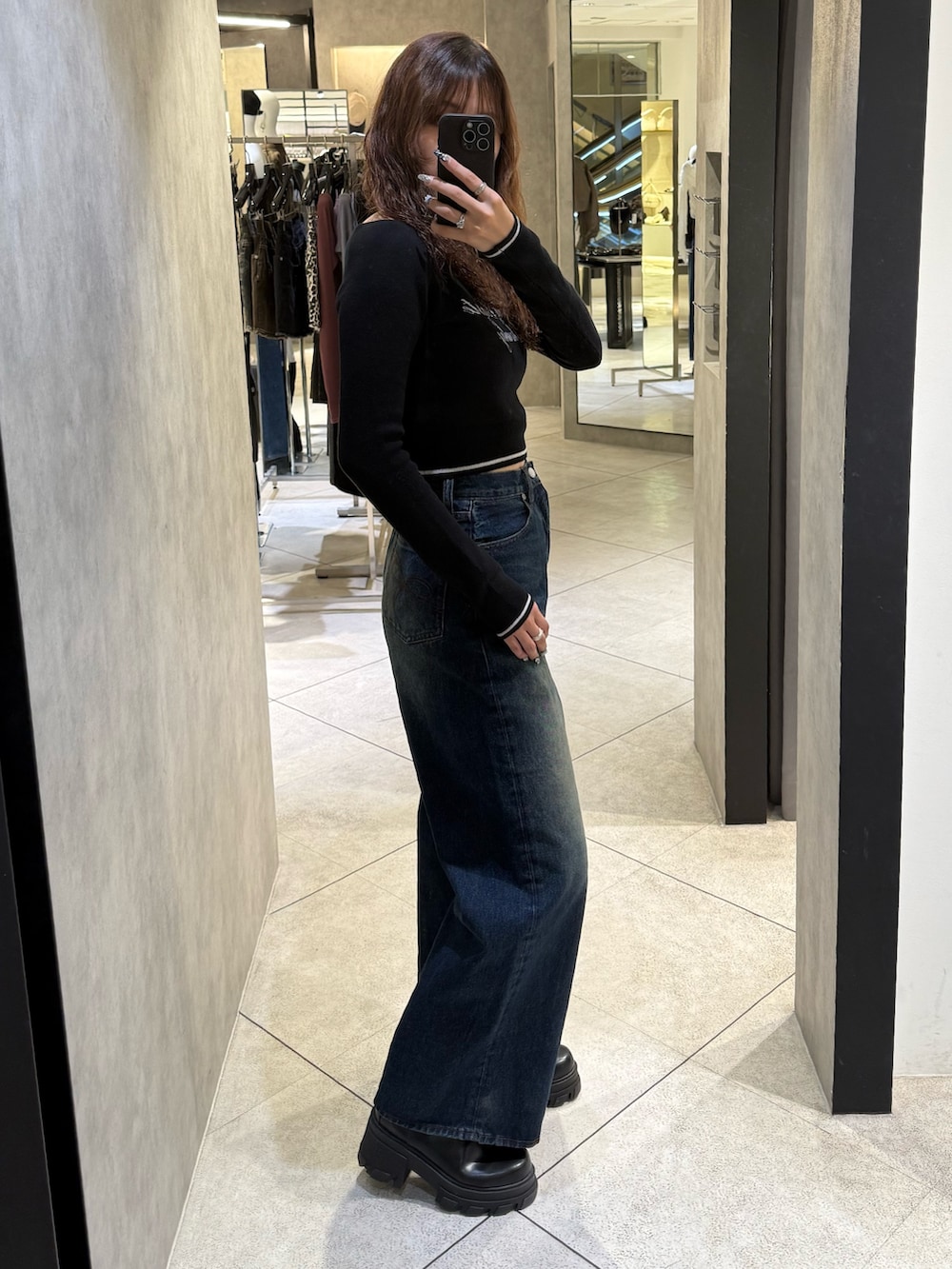 ブラック系のブーツ、ブラック系のニット/セーター、ブルー系のデニムパンツを着用したレディースの秋コーディネートの2枚目の写真