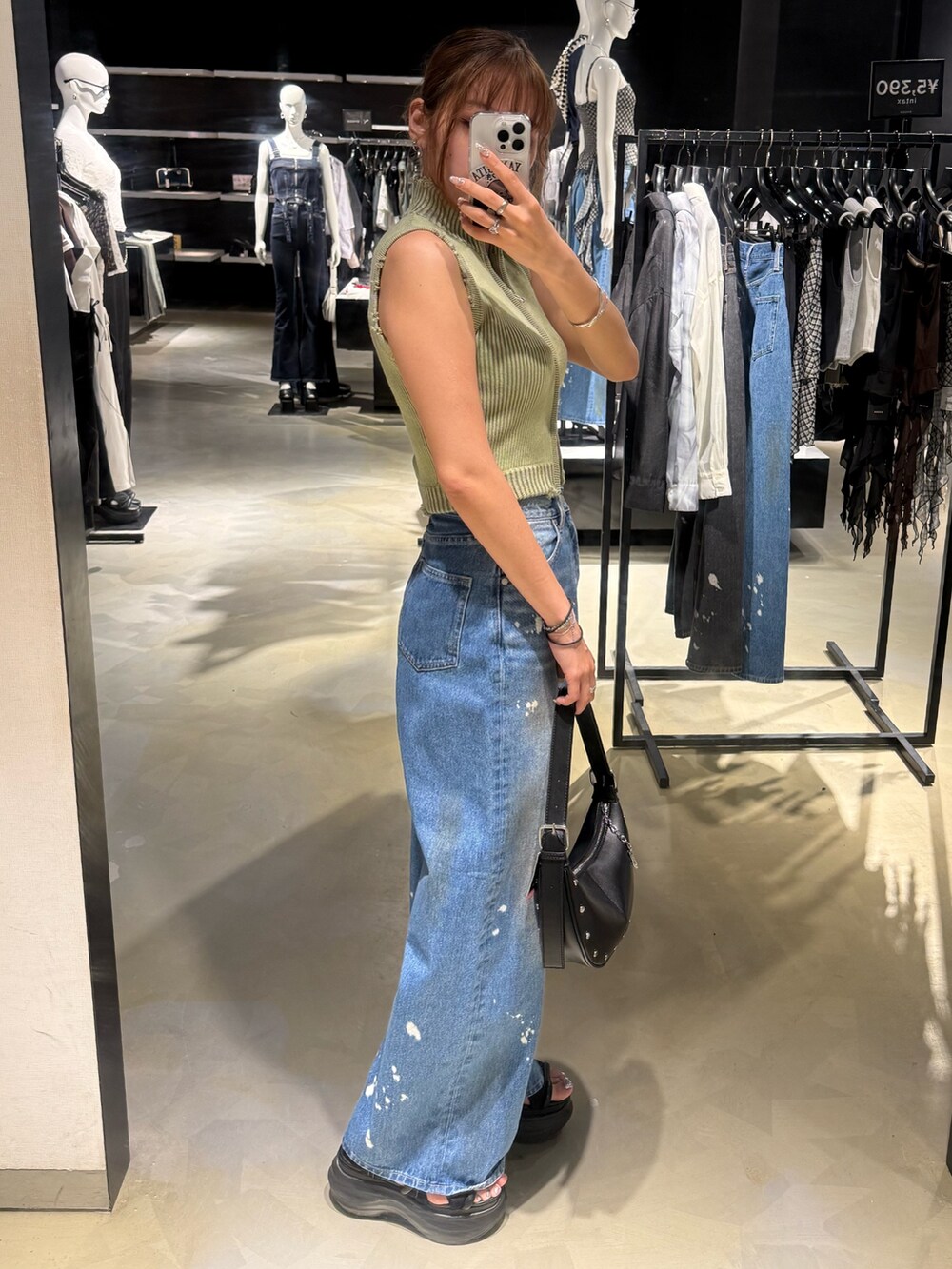 グリーン系のタンクトップ、ブルー系のデニムパンツ、ブラック系のハンドバッグを着用したレディースの夏コーディネートの2枚目の写真